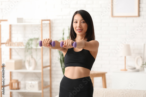 Beautiful young Asian woman with dumbbells at home. Weight loss concept