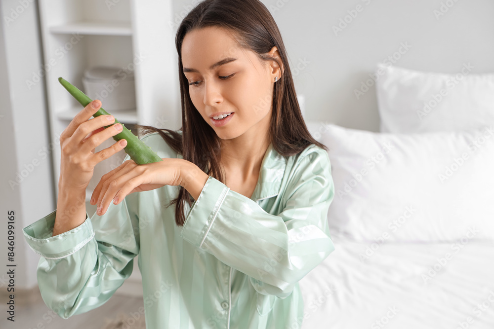 Beautiful young woman in pajamas with aloe vera at home Beautiful young woman in pajamas with aloe vera at home