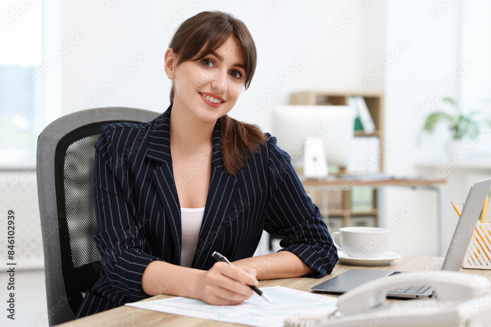 Portrait of smiling secretary at table in office Portrait of smiling secretary at table in office