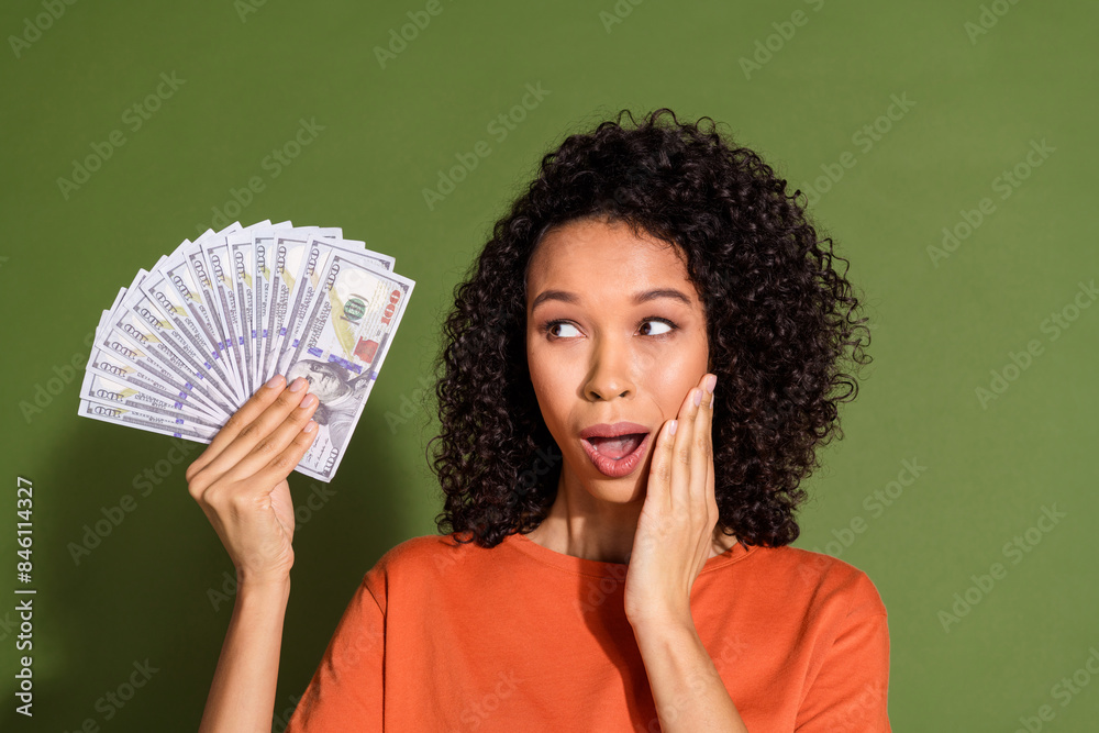 Photo portrait of lovely young lady look interested money fan dressed stylish orange garment isolated on khaki color background Photo portrait of lovely young lady look interested money fan dressed stylish orange garment isolated on khaki color background
