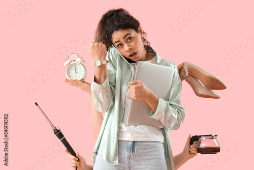 Hurrying young African-American woman and hands with things on pink background