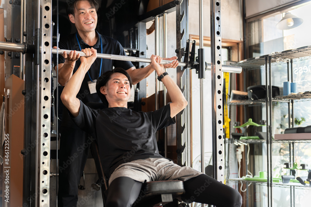 ジムでパーソナルトレーニングを受ける男性とトレーナー・インストラクターの男性
