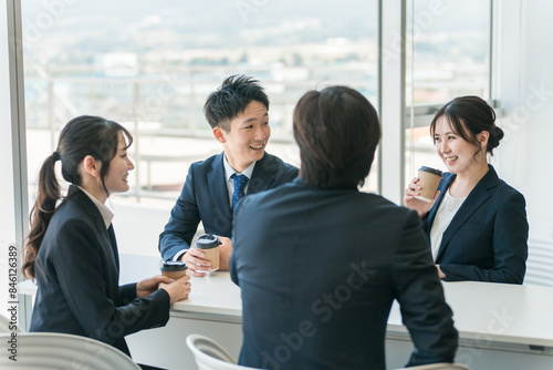 オフィスの休憩スペースで談笑するビジネスマン男女
