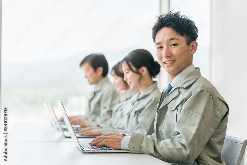 デスクワークする作業着・作業服姿の男女ビジネスマン・エンジニア
