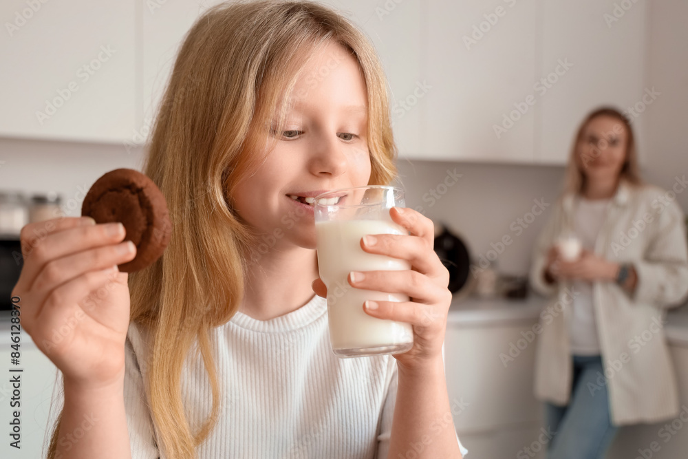 Happy daughter and her mother with cups of milk and tasty cookie in kitchen at home Happy daughter and her mother with cups of milk and tasty cookie in kitchen at home