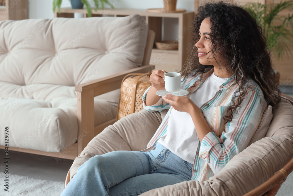 Young African-American woman with cup of coffee resting in armchair at home Young African-American woman with cup of coffee resting in armchair at home