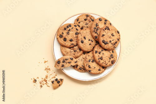 Plate of sweet cookies with chocolate chips on beige background photo