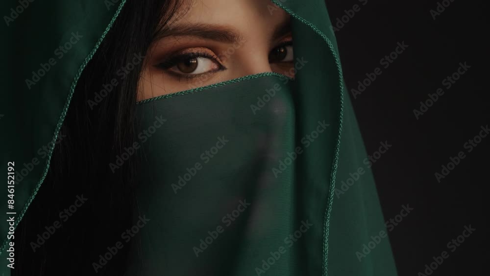 Mysterious Woman in Green Veil with Intense Eyes on Dark Background