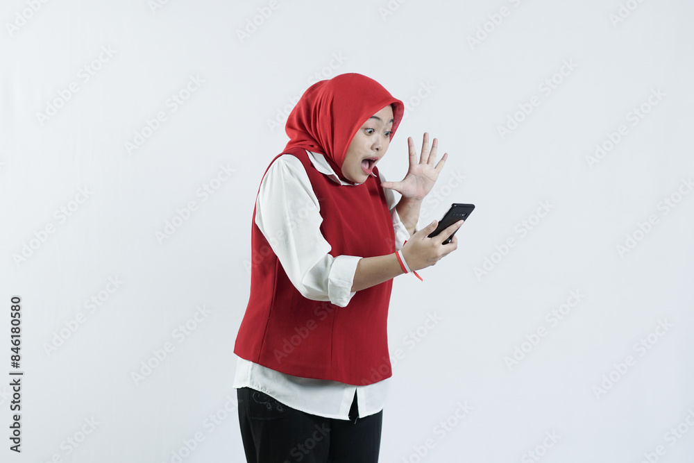 Asian hijab woman in looks happy in Indonesian independence day outfit using a cell phone. Asian hijab woman in looks happy in Indonesian independence day outfit using a cell phone.