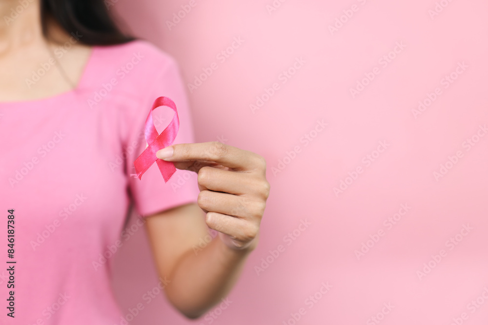 Woman Hand Holding Pink Ribbon Isolated On Pink Background For World Cancer Day Concept.