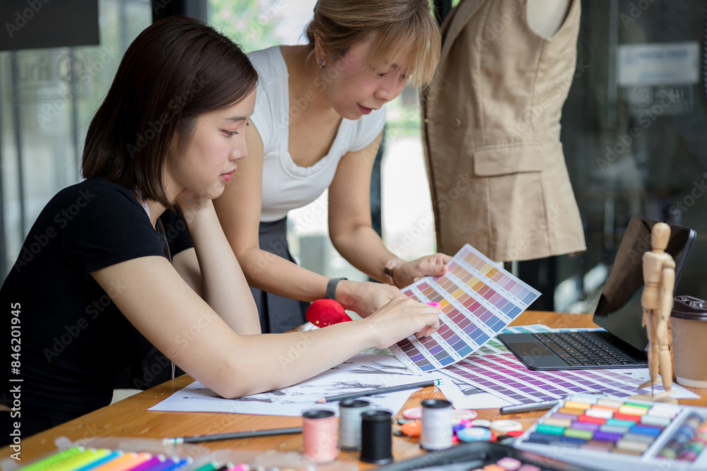 Fototapeta premium Young team asian designer women working at studio. Dressmaker makes clothes job