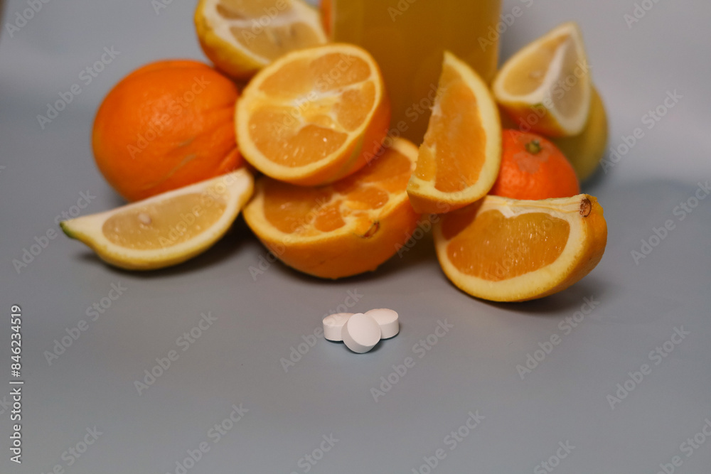 Orange and pieces of orange on the background of a glass of orange juice, white pills in front Orange and pieces of orange on the background of a glass of orange juice, white pills in front