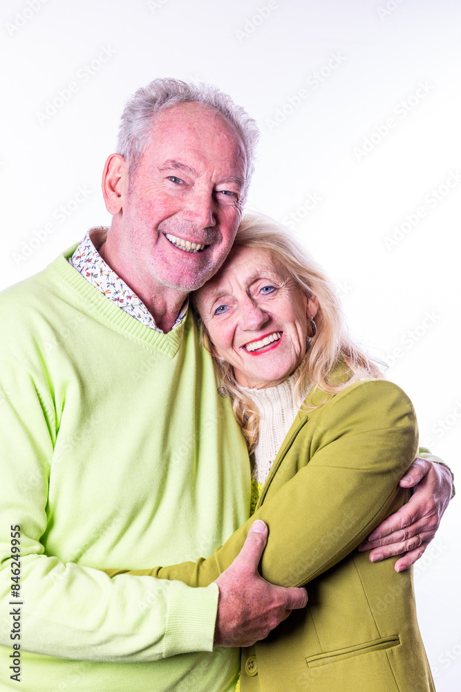 A joyous elderly couple in green casual attire embrace each other in a bright studio, exuding happiness and love A joyous elderly couple in green casual attire embrace each other in a bright studio, exuding happiness and love