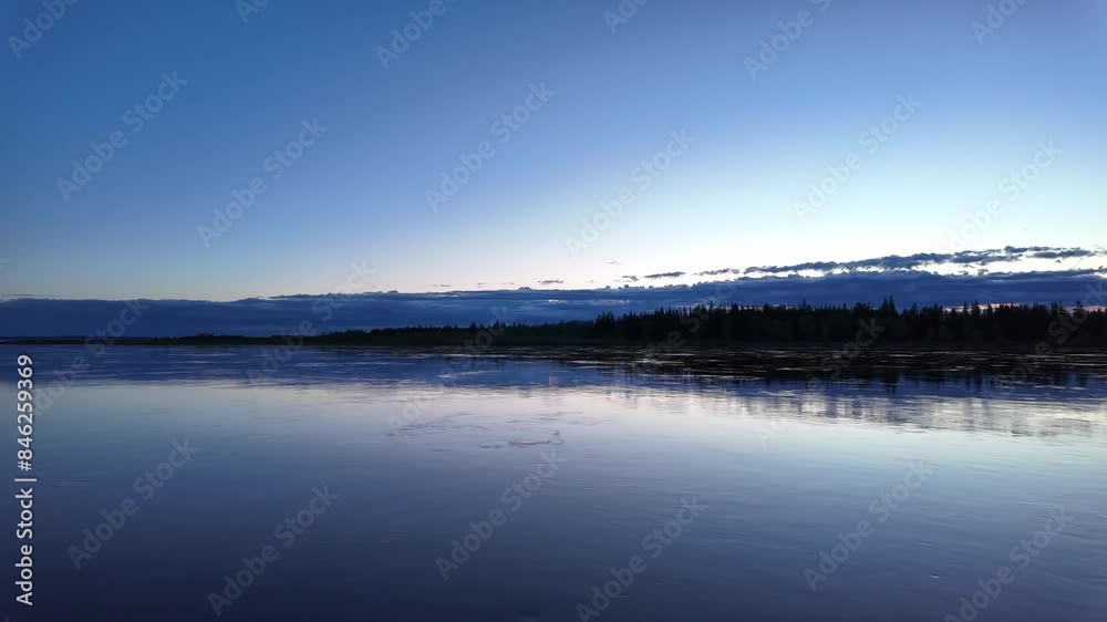A peaceful evening view of a calm river with a beautiful reflection of the sky and trees at dusk in Russia. A peaceful evening view of a calm river with a beautiful reflection of the sky and trees at dusk in Russia.