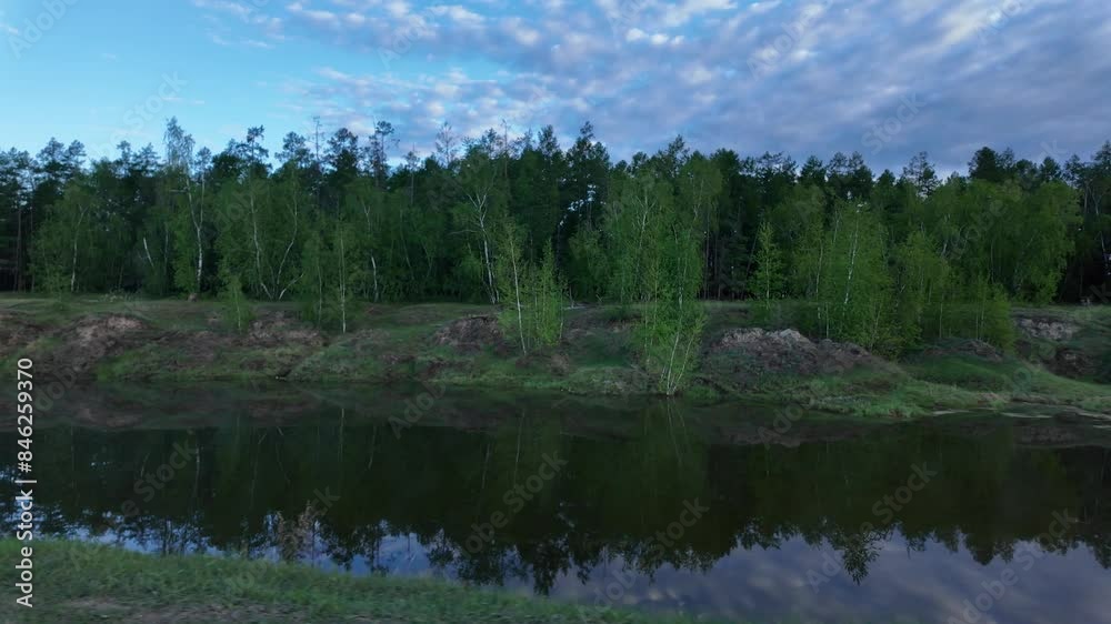 A peaceful pond reflects the sky at sunrise in a beautiful forest setting. A peaceful pond reflects the sky at sunrise in a beautiful forest setting.