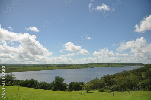 Lush green grass meadow under rural blue sky, grass texture and beautiful lake in the background. Beautiful morning light on green grass farm. the lake of Barragem da Pedra do Cavalo photo