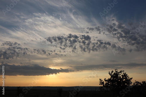 The sunset scene shows dramatic clouds over peaceful countryside fields under the twilight sky