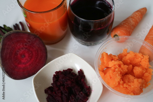 beet root juice and carrot juice. Healthy drink, cold pressed juice, served in glass with fresh beetroot, carrot and ginger. and the juice dregs on the tiny bowl. photo