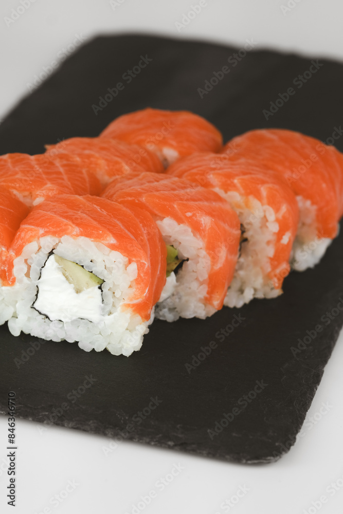 Closeup of fresh salmon sushi rolls served on a black slate plate Closeup of fresh salmon sushi rolls served on a black slate plate