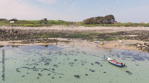 Guernsey, Channel Islands.Forward flight over crystal clear shallow water on golden beach with small boats drying out at low tide on sunny day photo