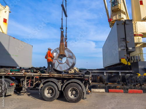 Loading of hot rolled steel coils on board of cargo ship using braided wire slings and heavy crane.