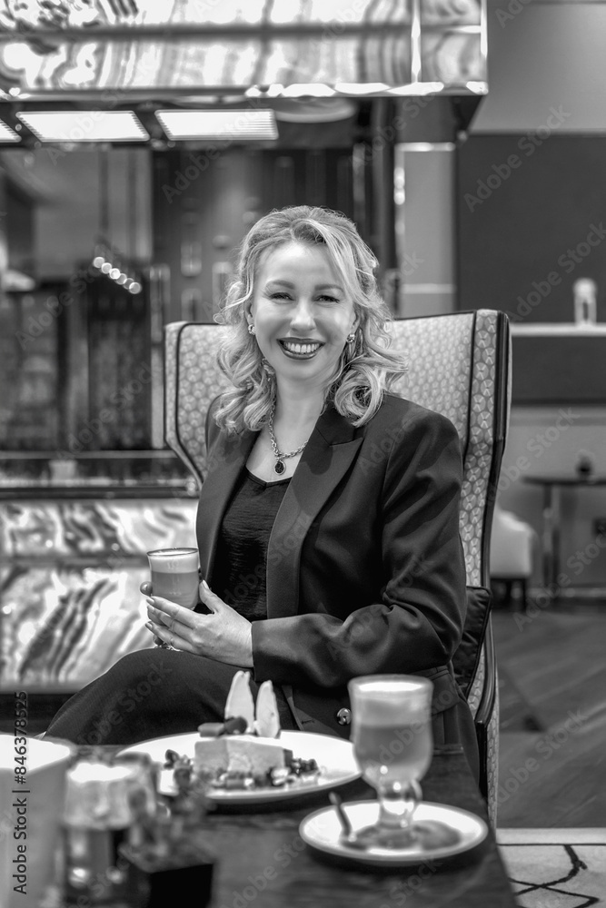 A middle-aged smiling blonde in a stylish business suit stands in the business center. The concept of a stylish office image, a business woman A middle-aged smiling blonde in a stylish business suit stands in the business center. The concept of a stylish office image, a business woman