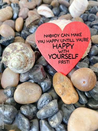 Inspirational quote - Nobody can make you happy until you're happy with yourself first on heart shape with stones background.