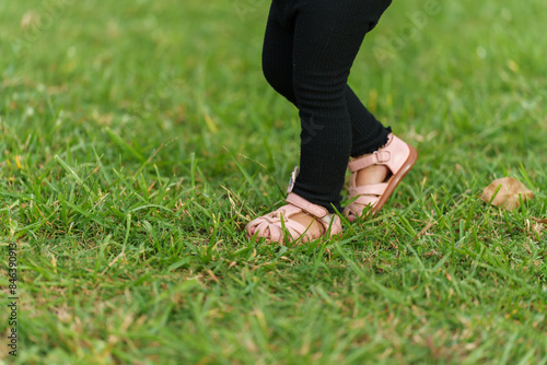 close up leg of toddler baby walking in grass field.