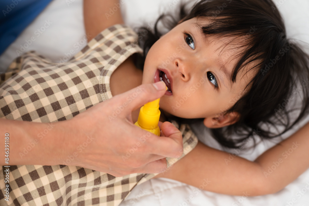 mother or doctor spraying medicine in mouth of toddler. baby sore throat treatment concept mother or doctor spraying medicine in mouth of toddler. baby sore throat treatment concept