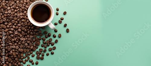 A mint colored background with a drip coffee bag filled with ground coffee beans for brewing in a cup Scattered coffee beans surround the bag on a minimal flat lay with a pastel colored backdrop prov