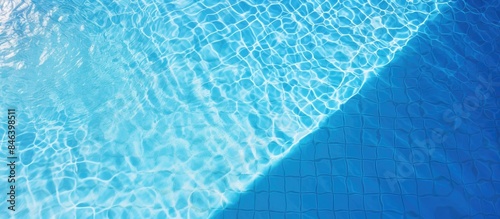 Aerial view of sunlight reflecting on the water surface of a blue tiled swimming pool creating a patterned background with ample copy space image