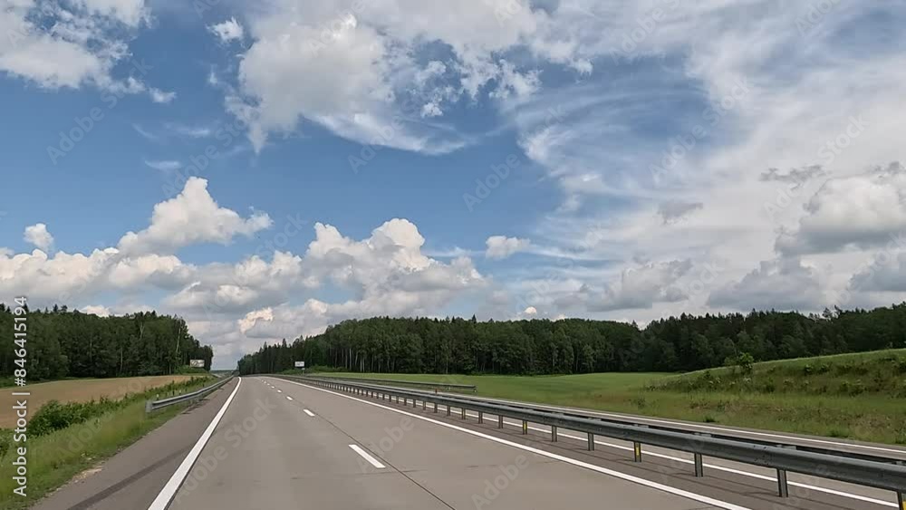 View back to the road on a summer day from a red car. Highways and roadsides move away from the car. View back to the road on a summer day from a red car. Highways and roadsides move away from the car.