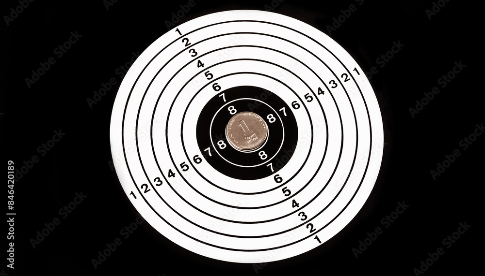 Israeli 1 shekel coin in the center of a shooting target on a black background Israeli 1 shekel coin in the center of a shooting target on a black background