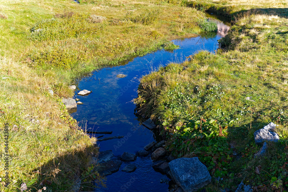 Alpine landscape at hiking trail with creek at Swiss mountain pass Gotthard on a sunny late summer day. Photo taken September 10th, 2023, Gotthard, Switzerland. Alpine landscape at hiking trail with creek at Swiss mountain pass Gotthard on a sunny late summer day. Photo taken September 10th, 2023, Gotthard, Switzerland.