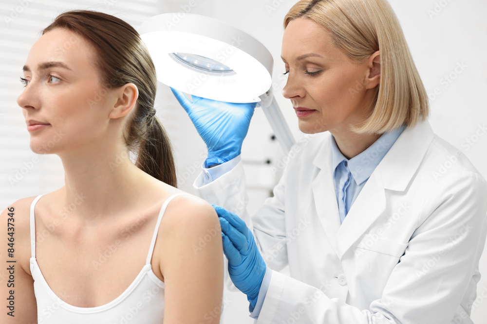 Dermatologist examining patient under lamp in clinic Dermatologist examining patient under lamp in clinic