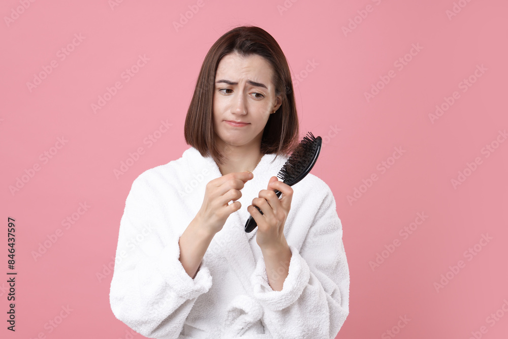 Sad woman holding brush with lost hair on pink background. Alopecia problem Sad woman holding brush with lost hair on pink background. Alopecia problem
