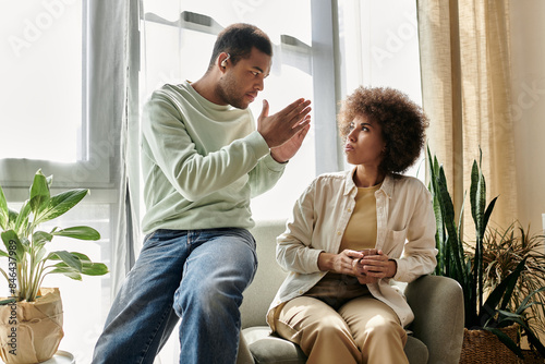 An African American couple sits at home and communicates through sign language.