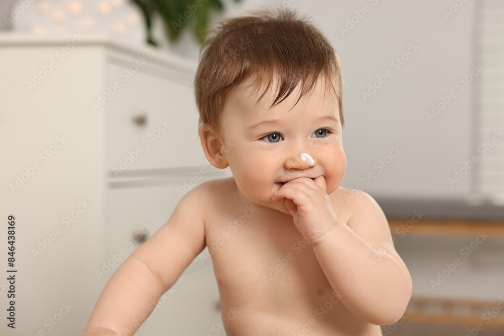 Cute little baby with moisturizing cream on face indoors Cute little baby with moisturizing cream on face indoors