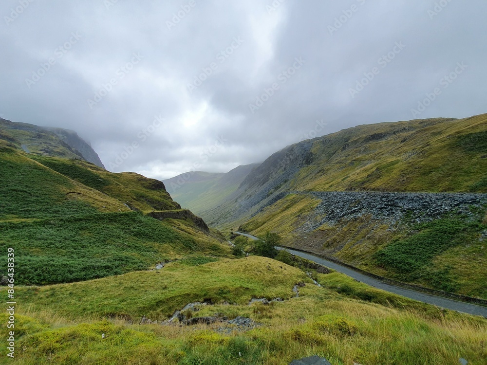 Scenic road through lush green valley with rolling hills on each side Scenic road through lush green valley with rolling hills on each side