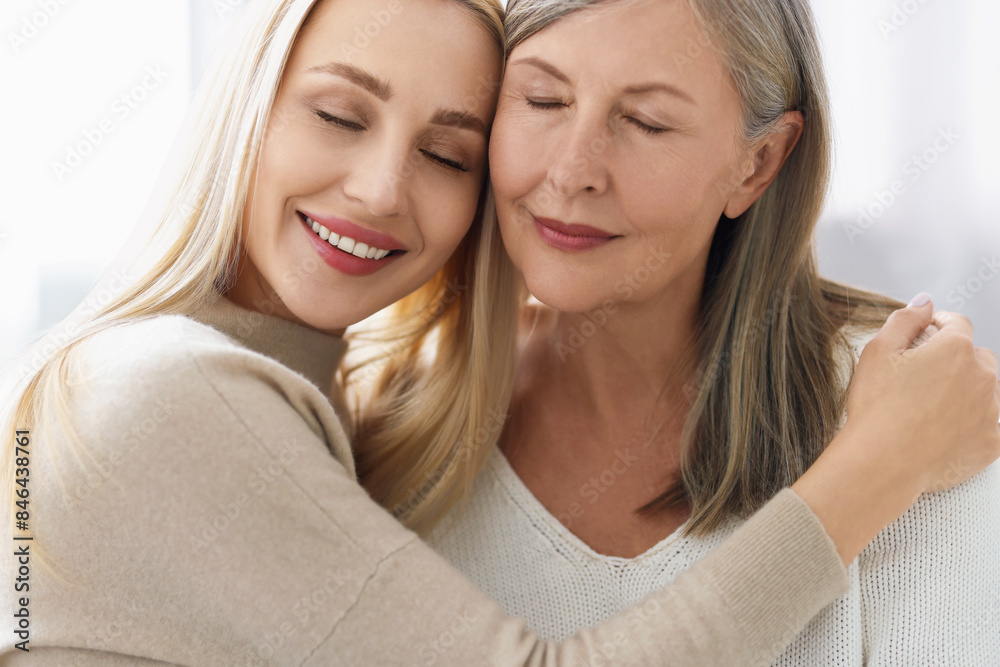 Family portrait of young woman and her mother on light background Family portrait of young woman and her mother on light background