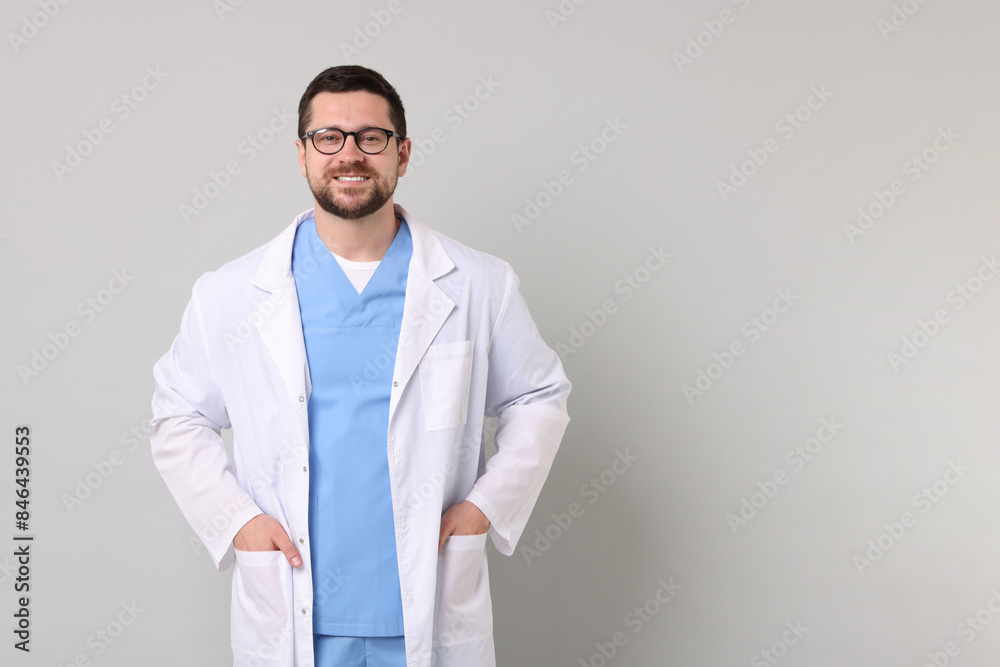 Portrait of smiling doctor on light grey background. Space for text