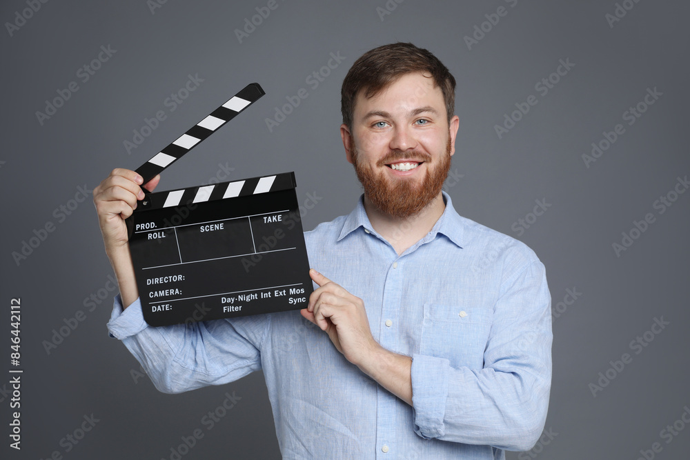 Making movie. Smiling man with clapperboard on grey background Making movie. Smiling man with clapperboard on grey background