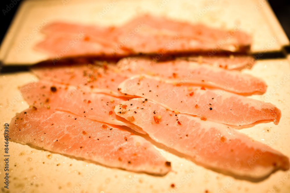 Bacon slices on a wooden cutting board with a knife and pepper Bacon slices on a wooden cutting board with a knife and pepper