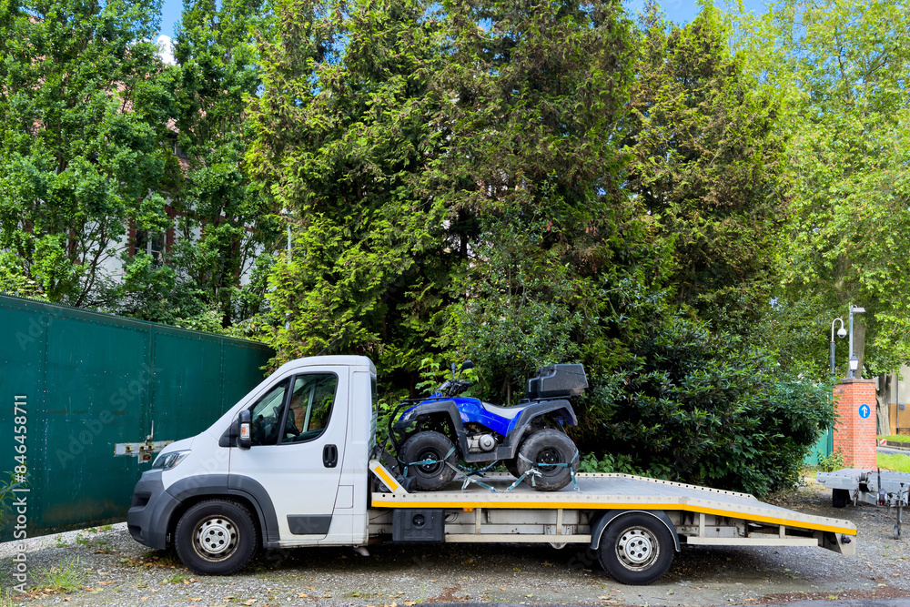 Fototapeta premium A blue ATV quad bike loaded into the back of a small car.