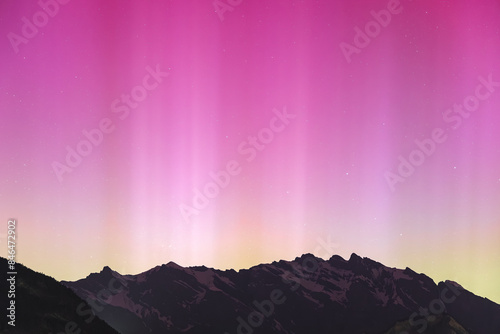 Pink northern lights landscape over a mountain range in the Swiss Alps photo