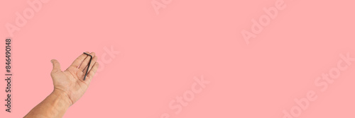 Black male hand offering an allen key isolated on pink background banner