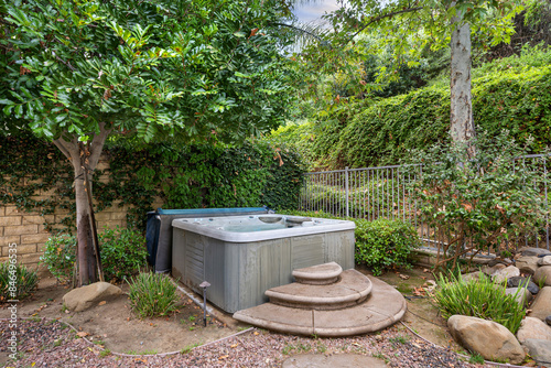 Backyard featuring a hot tub surrounded by green trees. California, USA © Wirestock