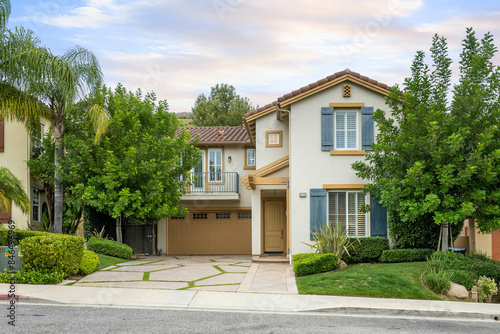 Two-story house with a garage and front yard trees. California, USA
