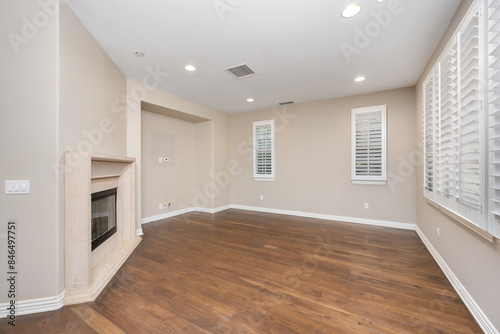 Fotografi Spacious room with hardwood floors and windows with white blinds