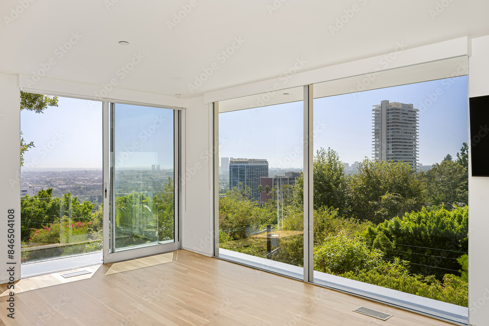 Fototapeta premium Spacious bedroom with large windows, hardwood floors, and a television
